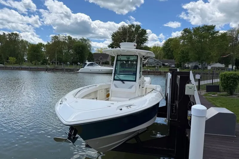 Slide: The Image of 2015 Boston Whaler 280 Outrage boat docked on a scenic lake under a cloudy sky. - 3