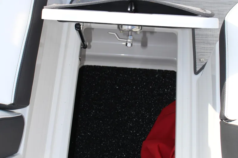 Slide: The Image of Open storage compartment in 2026 Cobalt R6 boat, featuring black interior and red item. - 17