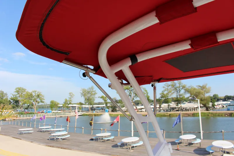 Slide: The Image of Red canopy of 2026 Cobalt R6 boat overlooking a scenic waterfront with trees and tables. - 51