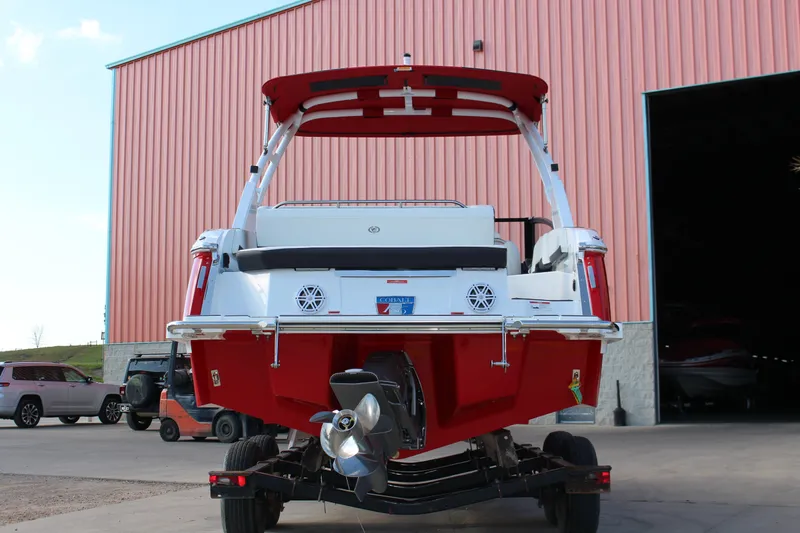 Slide: The Image of 2026 Cobalt R6 boat in red, rear view, parked outside a large building. - 70