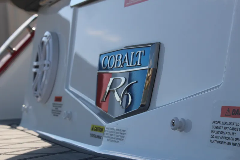 Slide: The Image of 2026 Cobalt R6 boat emblem on white surface with speaker and caution labels. - 80