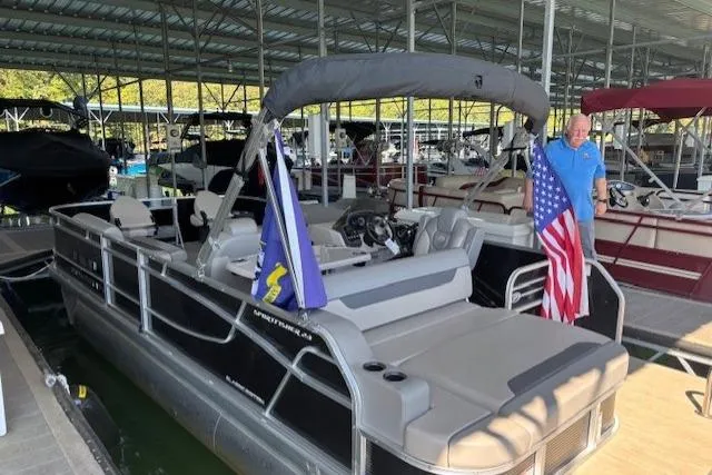 Slide: The Image of 2022 Princecraft Sportfisher 23-2S RL pontoon boat docked with flags displayed. - 19