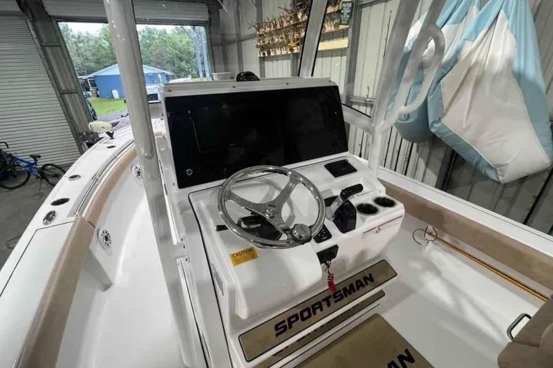 Slide: The Image of 2020 Sportsman Masters 267OE Bay Boat interior with steering wheel and console in a garage. - 5