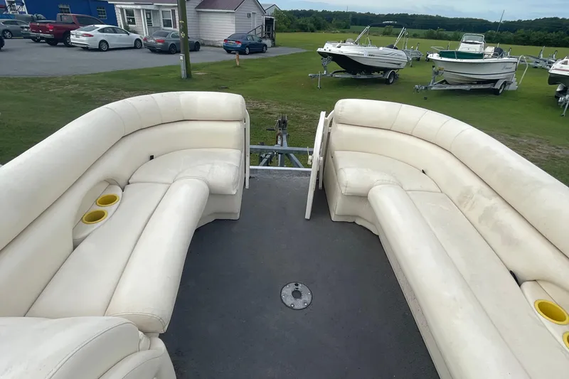 Slide: The Image of 2006 Starcraft Elite 226 boat interior with white seating and cup holders, parked outdoors. - 6