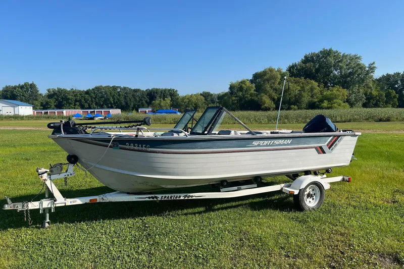 Slide: The Image of 1987 Blue Fin Sportsman boat on trailer, parked on grassy field under clear blue sky. - 1