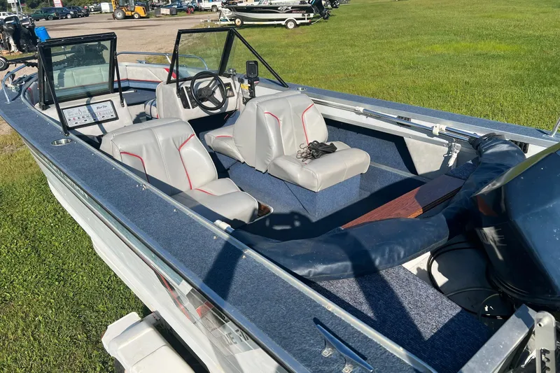 Slide: The Image of 1987 Blue Fin Sportsman boat interior with gray seats and steering wheel, parked on grass. - 7