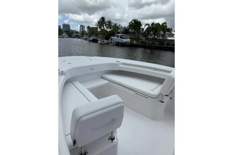 Slide: The Image of 2026 Southport 30 FE boat interior with white seating, docked near palm trees and buildings. - 16