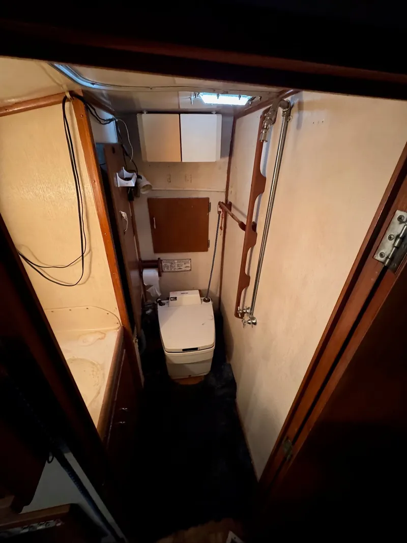Slide: The Image of 1963 Hatteras Sport Fisherman boat bathroom interior with compact toilet and wooden accents. - 24