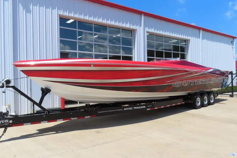 Slide: The Image of 2004 Outerlimits 42 Legacy speedboat on trailer, parked outside a modern building. - 1