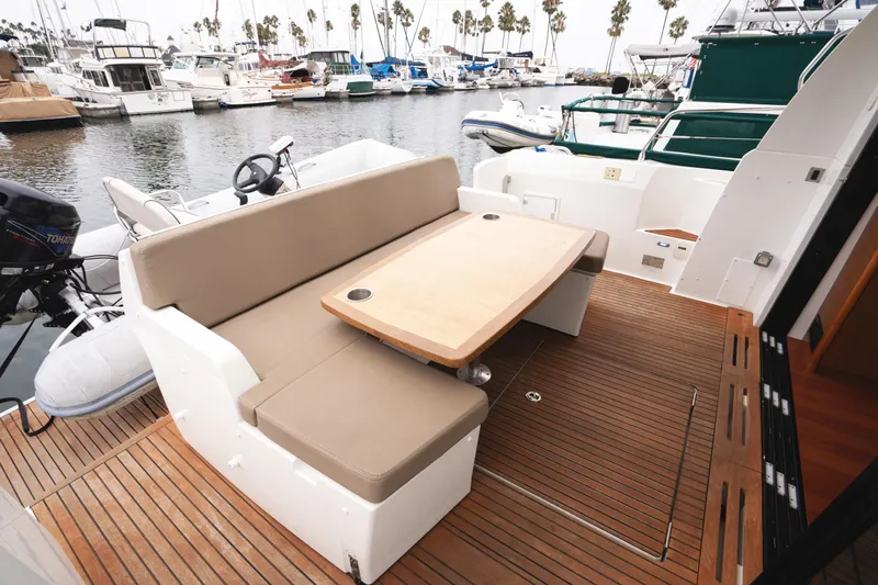 Slide: The Image of 2014 Jeanneau NC 14 yacht with outdoor seating and table, docked at marina. - 10