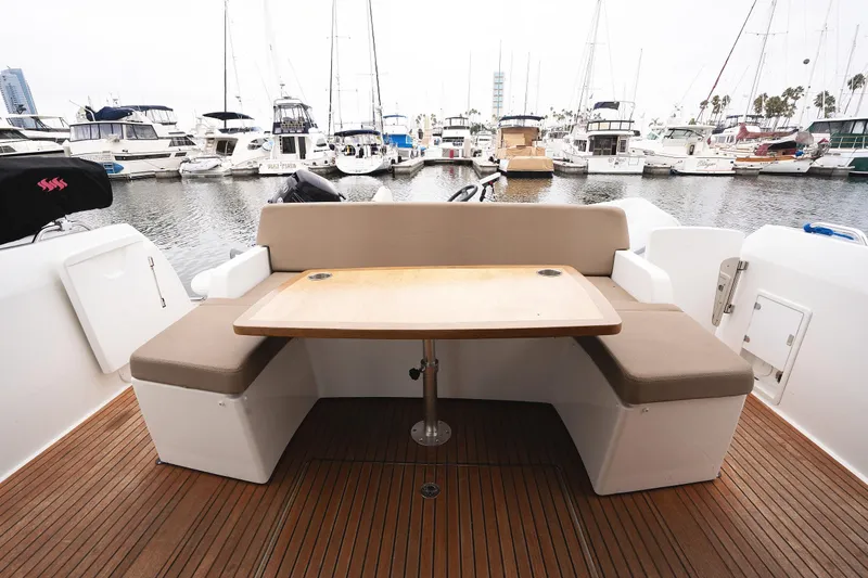 Slide: The Image of 2014 Jeanneau NC 14 yacht with outdoor seating and table, docked at marina. - 11