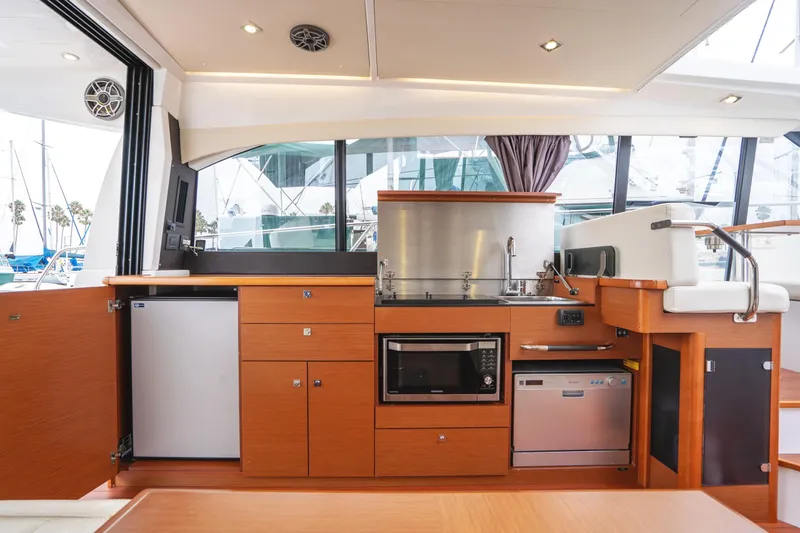 Slide: The Image of 2014 Jeanneau NC 14 yacht interior kitchen with modern appliances and sleek wood cabinetry. - 17