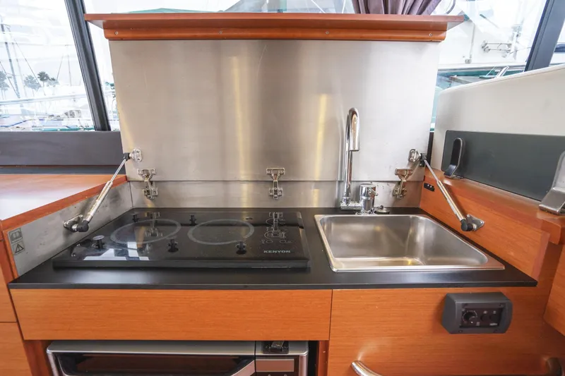 Slide: The Image of 2014 Jeanneau NC 14 yacht kitchen with stove and sink, featuring modern design and functionality. - 18