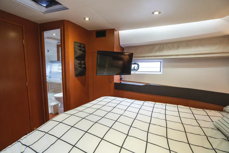 Slide: The Image of 2014 Jeanneau NC 14 yacht bedroom with modern decor, TV, and ensuite bathroom. - 35
