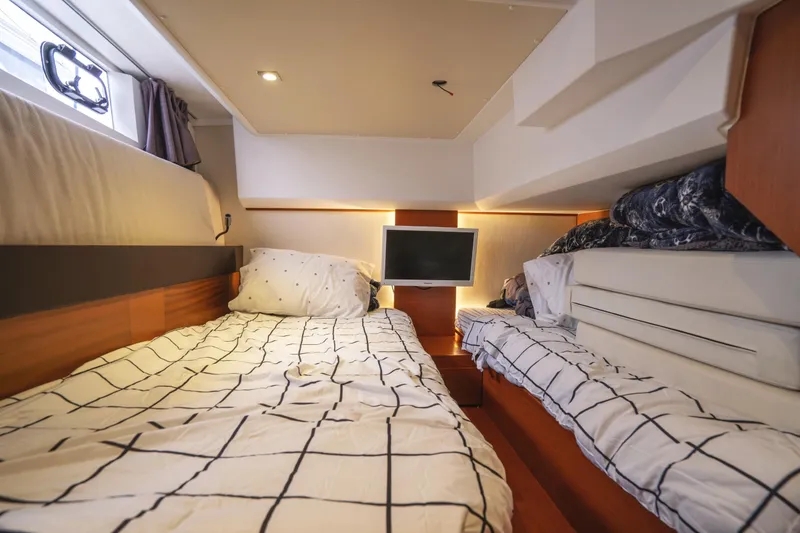 Slide: The Image of 2014 Jeanneau NC 14 cabin interior with twin beds and a small TV. - 40