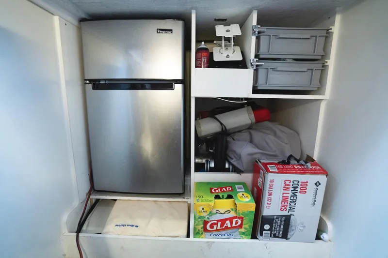 Slide: The Image of Storage area in a 2014 Jeanneau NC 14 with fridge and supplies. - 56