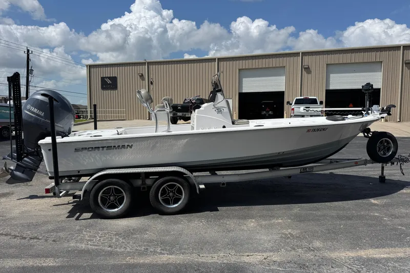 Slide: The Image of 2023 Sportsman Tournament 214 SBX Bay Boat on trailer, parked outside a warehouse. - 6