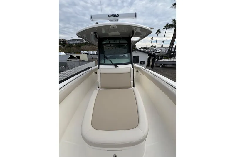 Slide: The Image of 2026 Boston Whaler 330 Outrage boat with cushioned seating and Simrad electronics. - 13
