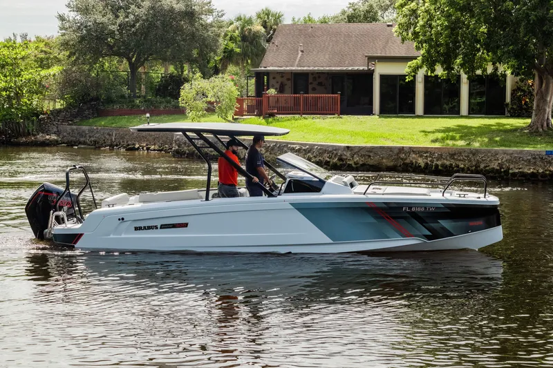 Slide: The Image of 2023 BRABUS Shadow 300 XT boat cruising on a calm river near a house. - 1