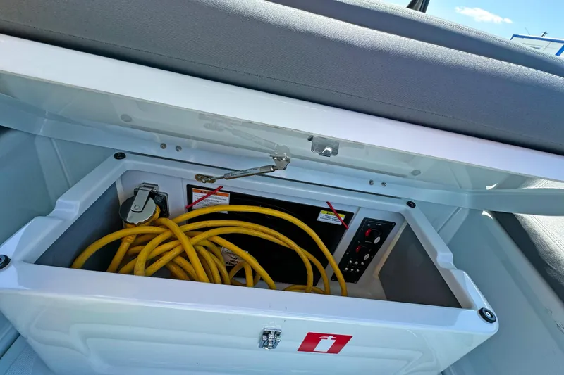 Slide: The Image of Storage compartment in 2023 BRABUS Shadow 300 XT with yellow cables and control panel. - 18
