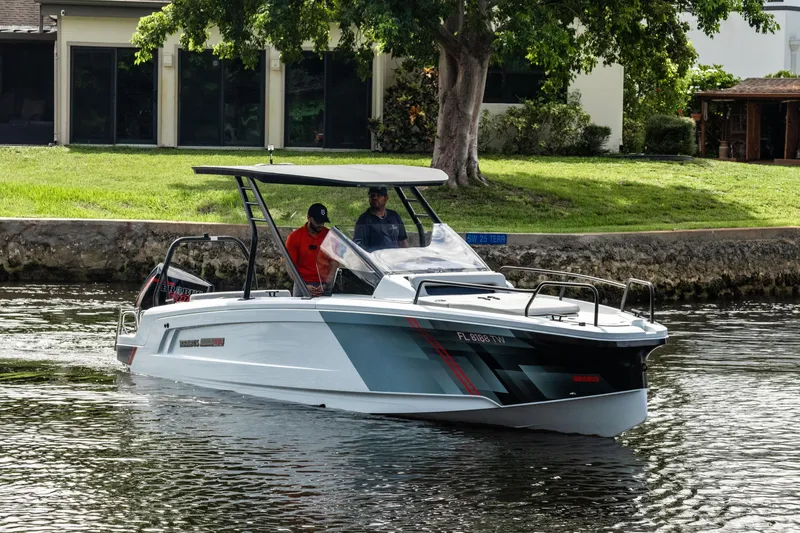 Slide: The Image of 2023 BRABUS Shadow 300 XT boat cruising on a calm waterway near a grassy shoreline. - 3