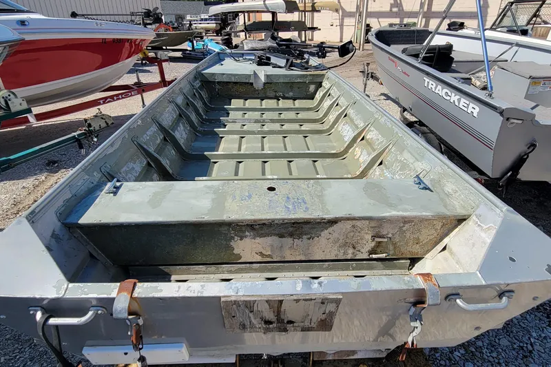 The Image of 1973 Monark 14 Jon boat in a lot, surrounded by other boats. - 0