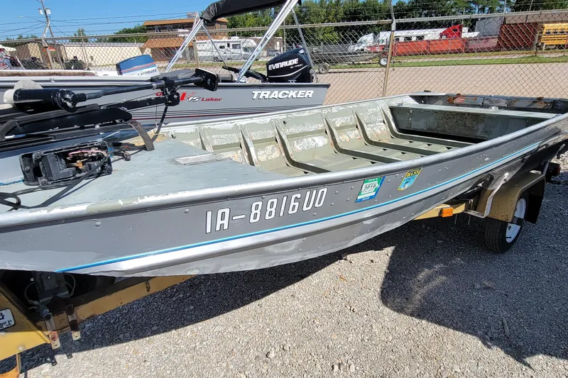 Slide: The Image of 1973 Monark 14 Jon boat on trailer, parked outdoors, with visible registration number. - 1