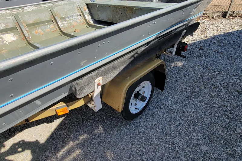 Slide: The Image of 1973 Monark 14 Jon boat on trailer, showing weathered interior and gravel ground. - 4
