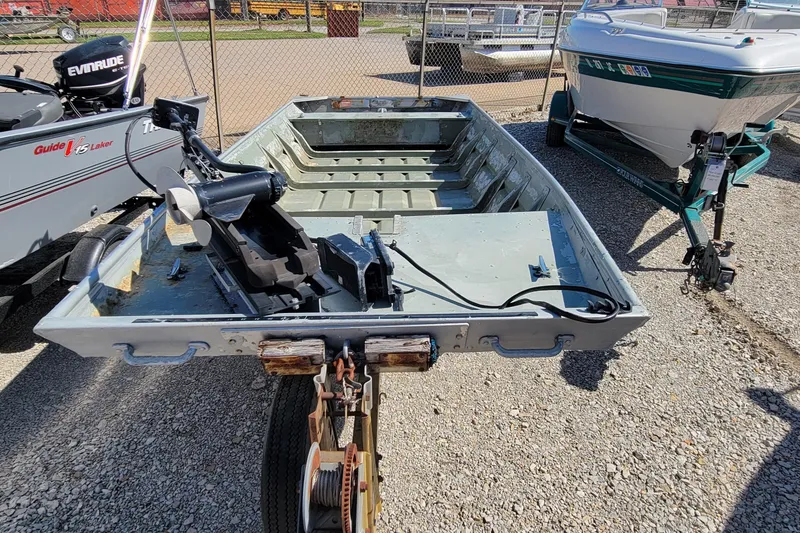 Slide: The Image of 1973 Monark 14 Jon boat on trailer, showing weathered interior and gravel ground. - 6