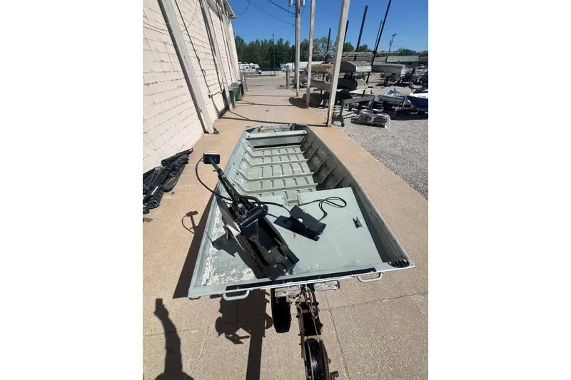 Slide: The Image of 1973 Monark 14 Jon boat on trailer, parked outdoors under clear sky. - 8