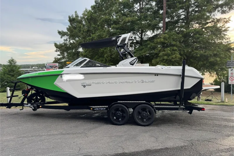 Slide: The Image of 2017 Nautique Super Air Nautique G23 boat on trailer, green and white design, parked outdoors. - 1