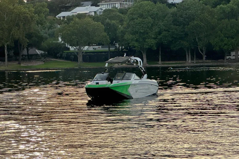 Slide: The Image of 2017 Nautique Super Air Nautique G23 boat on a serene lake with lush greenery. - 3