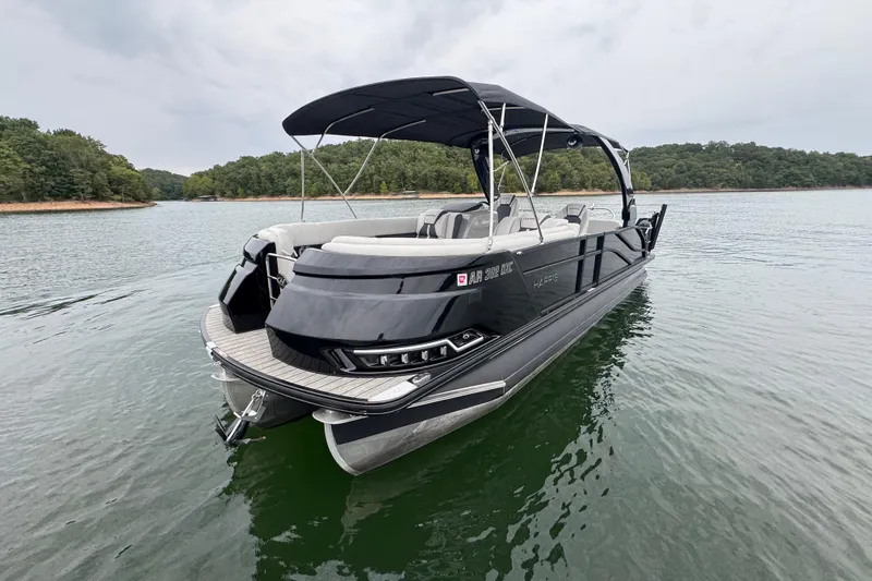 Slide: The Image of 2023 Harris Grand Mariner 250 pontoon boat on a calm lake, featuring sleek design. - 2