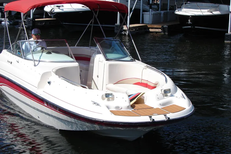 Slide: The Image of 1999 Chaparral Sunesta 233 boat with red canopy, docked on calm water. - 1