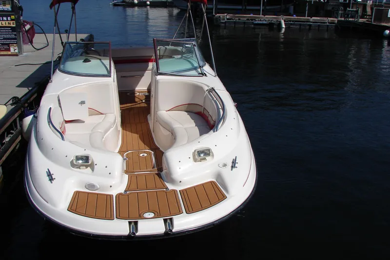 Slide: The Image of 1999 Chaparral Sunesta 233 boat docked on calm water, featuring spacious seating. - 24