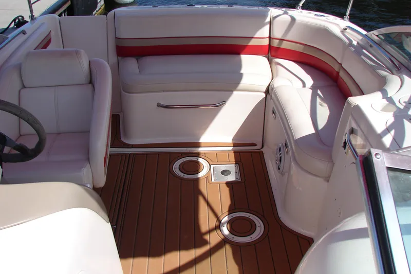 Slide: The Image of 1999 Chaparral Sunesta 233 boat interior with white and red seating, wooden deck. - 27