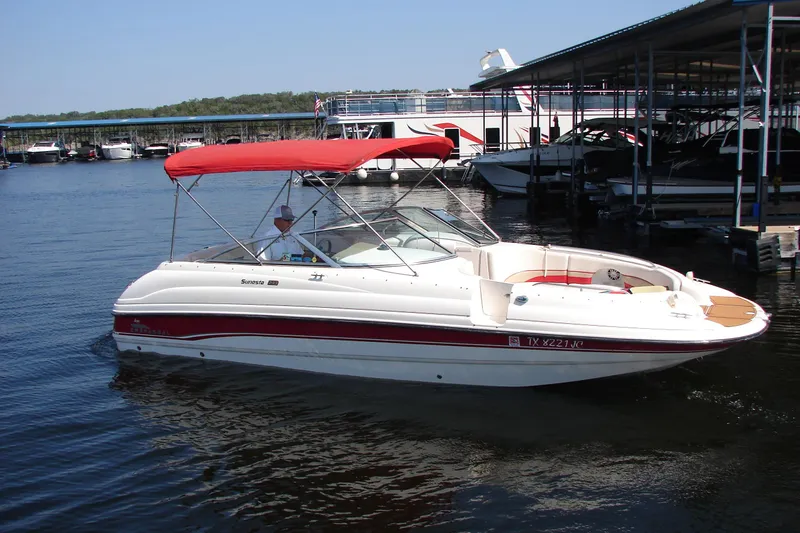 Slide: The Image of 1999 Chaparral Sunesta 233 boat with red canopy docked on calm water. - 3