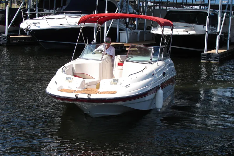 Slide: The Image of 1999 Chaparral Sunesta 233 boat with red canopy docked on calm water. - 9