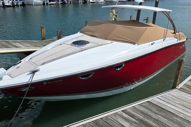 Slide: The Image of 2011 Cobalt 323 boat docked, featuring a red hull and tan cover. - 10