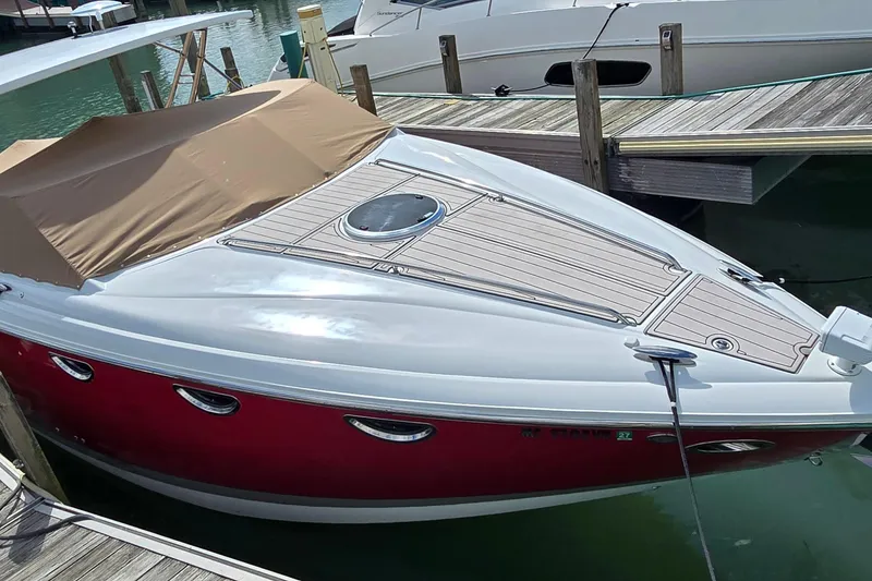 Slide: The Image of 2011 Cobalt 323 boat docked, featuring a red hull and tan cover. - 11