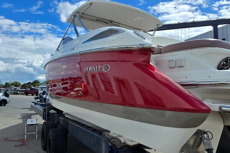 Slide: The Image of 2011 Cobalt 323 boat with red and white exterior on a trailer under a blue sky. - 2
