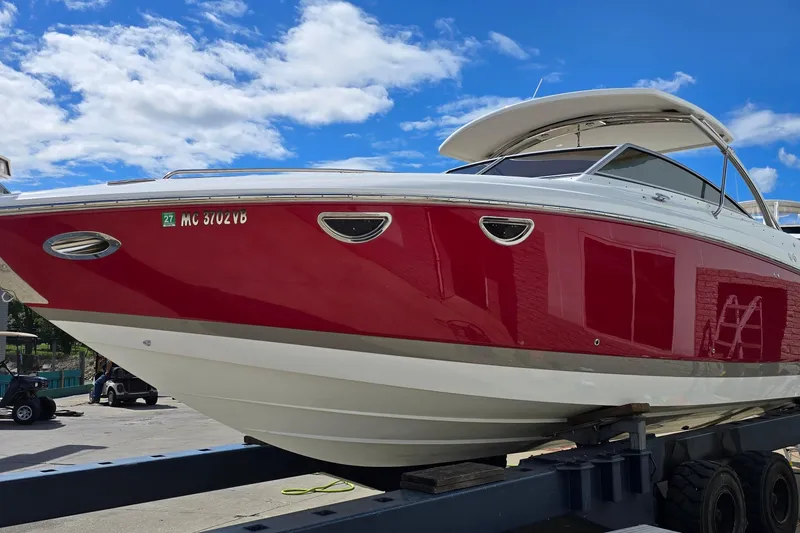 Slide: The Image of 2011 Cobalt 323 boat with red and white exterior on a trailer under a blue sky. - 3
