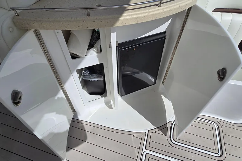 Slide: The Image of Open storage compartment on 2011 Cobalt 323 boat, featuring a mini fridge and supplies. - 30