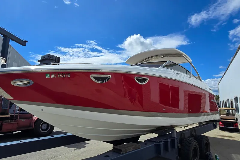 Slide: The Image of 2011 Cobalt 323 boat with red hull on a trailer under a clear blue sky. - 6