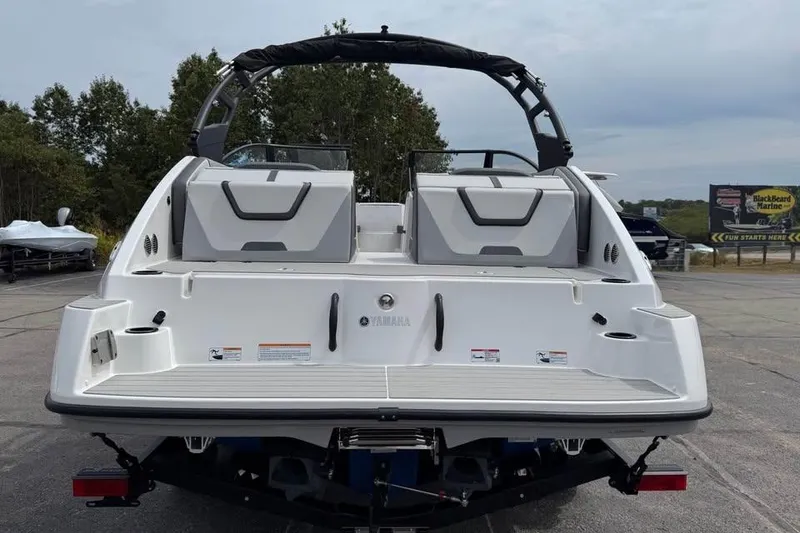 Slide: The Image of 2026 Yamaha Boats AR220, rear view, parked outdoors with trees in background. - 5