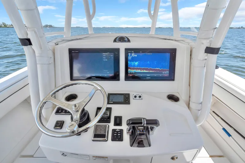 Slide: The Image of 2017 Jupiter 34 FS boat console with dual displays and steering wheel on open water. - 13