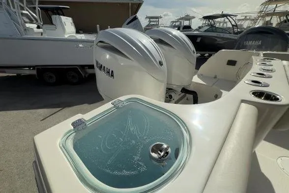 Slide: The Image of 2024 Sailfish 242 CC boat with Yamaha engines and livewell in marina setting. - 11