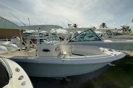Slide: The Image of 2024 Sailfish 242 CC boat displayed outdoors at a marina under a cloudy sky. - 14