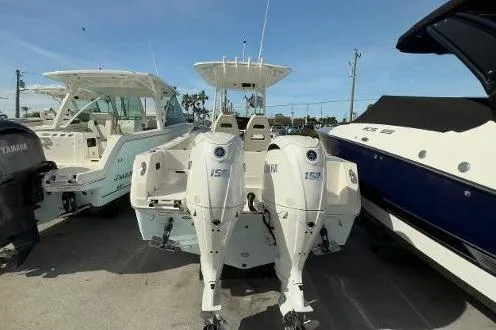 Slide: The Image of 2024 Sailfish 242 CC boat with dual outboard engines, docked alongside other boats. - 18
