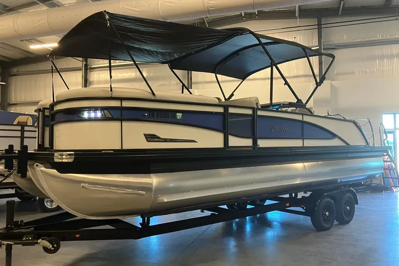 Slide: The Image of 2023 Barletta CORSA 25UE pontoon boat in a showroom, featuring a sleek design. - 25